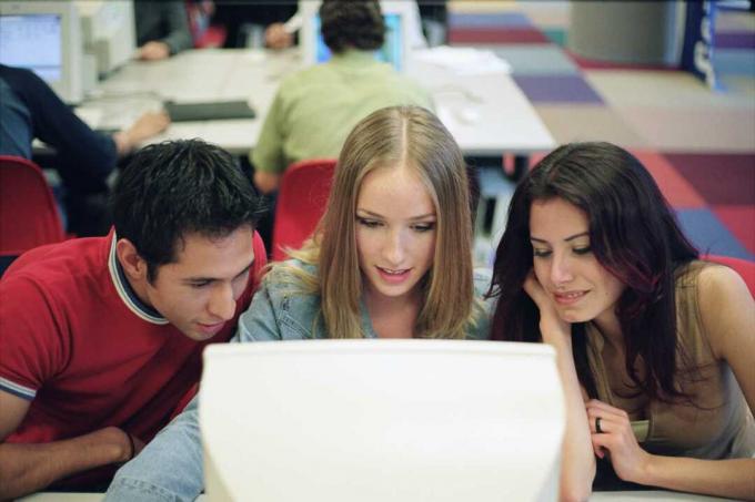 Tres estudiantes atentos a la pantalla de a computadora.