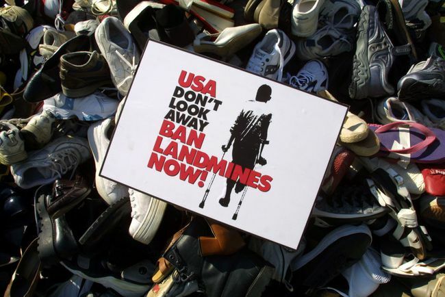 A taposóaknák tilalmát jelző tábla van elhelyezve egy piramison, amelyet az elmúlt néhány hónapban a taposóaknák tiltására irányuló amerikai kampány gyűjtött össze cipőkkel.