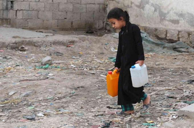 Egy kislány jótékonysági szivattyúból tiszta vízzel töltött kancsókat hordoz Jemenben folyamatos tiszta vízválság alatt