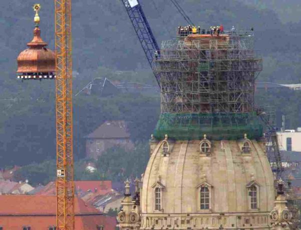 Egy daru felemeli a réz kupolát és az arany keresztet a rekonstruált Frauenkirche tetejére, Drezda, Németország