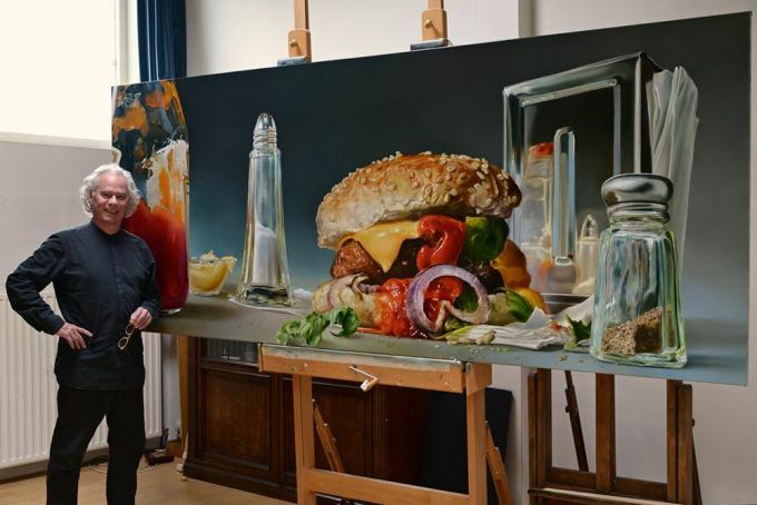 Az ember áll egy hamburger, só és bors rázógépek túlméretezett képe.
