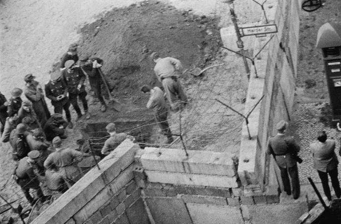 Kelet-német katonák csoportja a berlini fal alá ásott alagutat vizsgálja.