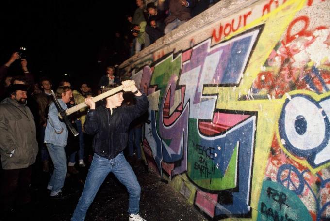 Egy ember csákányokkal támadja meg a berlini falat 1989. november 9-én éjjel