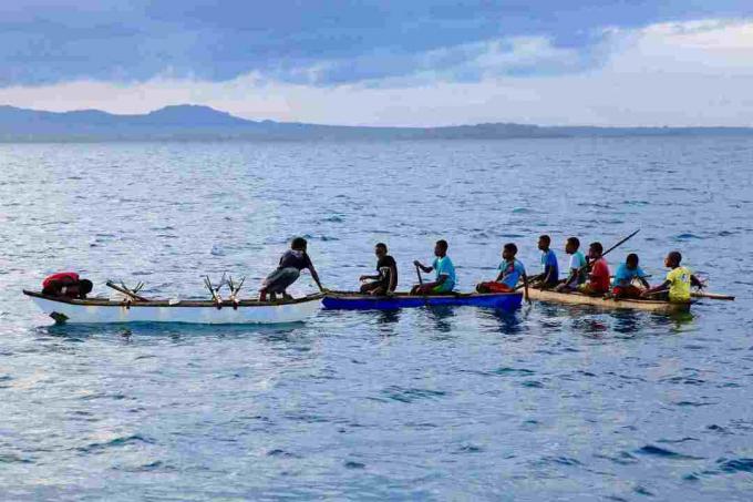 Fiatal férfiak kenukban északnyugati Malakula városában, Vanuatu.