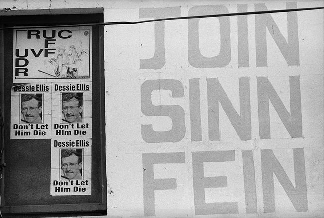Plakátok Észak-Írországban, amelyek a Sinn Fein politikai pártot támogatják, és összehasonlítják az észak-ír rendőrséget a brit hadsereggel.