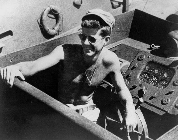 John F. Kennedy, félmeztelen, napszemüveget visel, miközben a PT-109 élén áll.