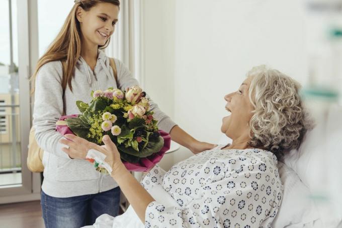 Unokája látogató nagymama a kórházban, hozva csokor virágot